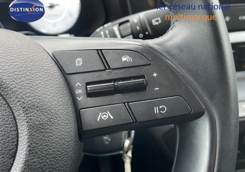 Gros plan sur les commandes au volant à droite d’une Hyundai i20 gris Aurora Metal, mettant en valeur les boutons de régulateur de vitesse.