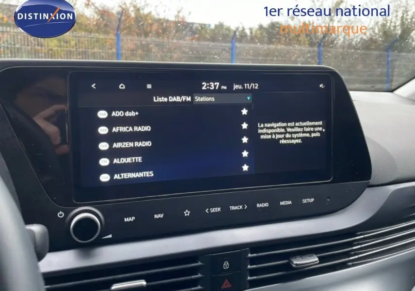Écran tactile central de la Hyundai i20 2025 affichant la liste des stations radio DAB/FM en intérieur gris.