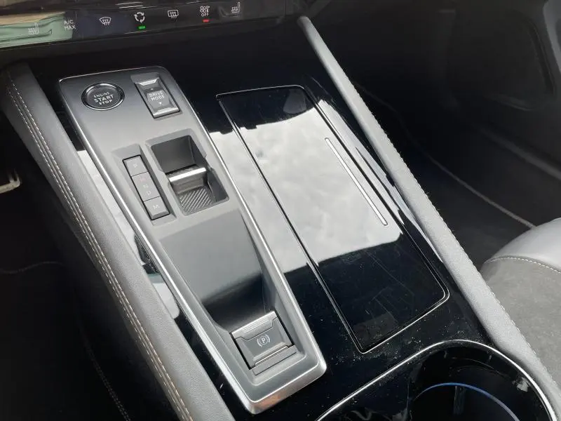 Gros plan sur la console centrale noire brillante du Peugeot 508 SW 2024 avec commandes de boîte auto et frein électrique.