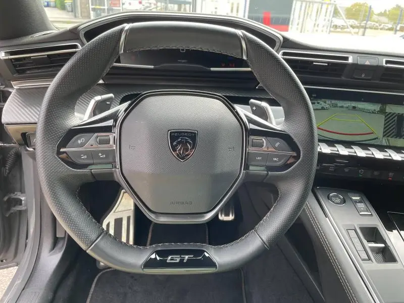 Vue centrée sur le volant cuir noir GT du Peugeot 508 SW Gris Selenium avec tableau de bord et écran de recul visible.