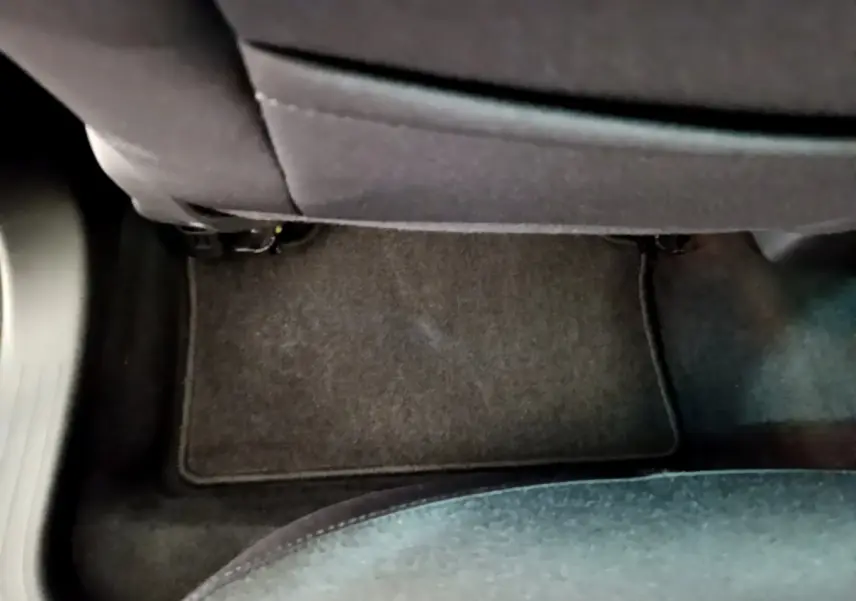 Vue rapprochée du tapis de sol noir sous le siège arrière d'une Renault Clio Business blanche de 2021.