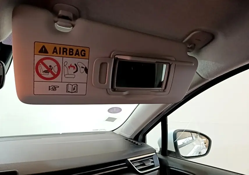 Intérieur de la Renault Clio Business blanc, vue côté passager avec pare-soleil et miroir ouvert.