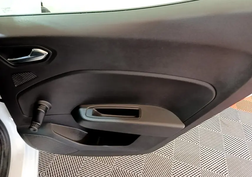 Vue intérieure sur la porte avant gauche noire d’une Renault Clio Business blanche, avec poignée et commande manuelle de vitre.