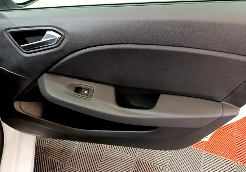 Vue rapprochée de la porte avant gauche noire de la Renault Clio Business blanche, avec poignée et commande de vitre.