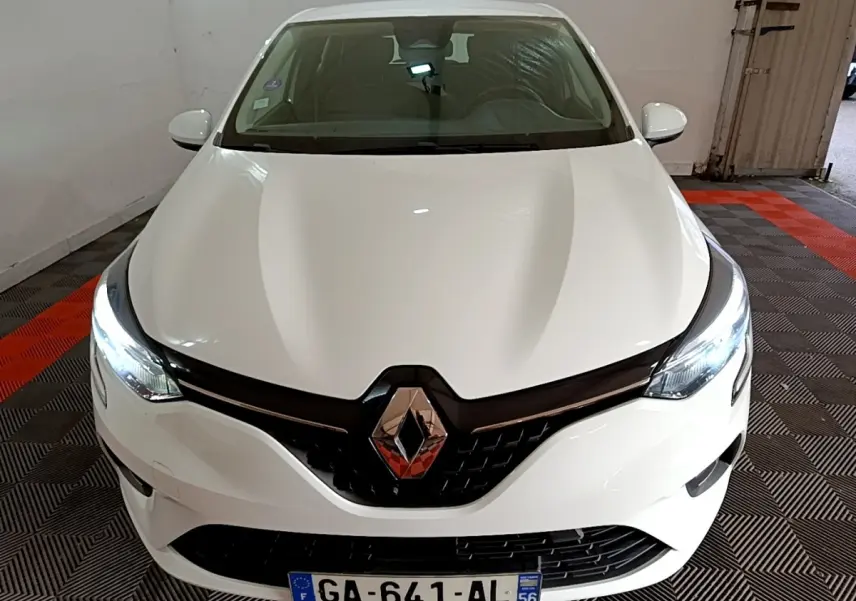 Vue avant d'une Renault Clio blanche 2021 avec phares LED allumés et calandre noire brillante.