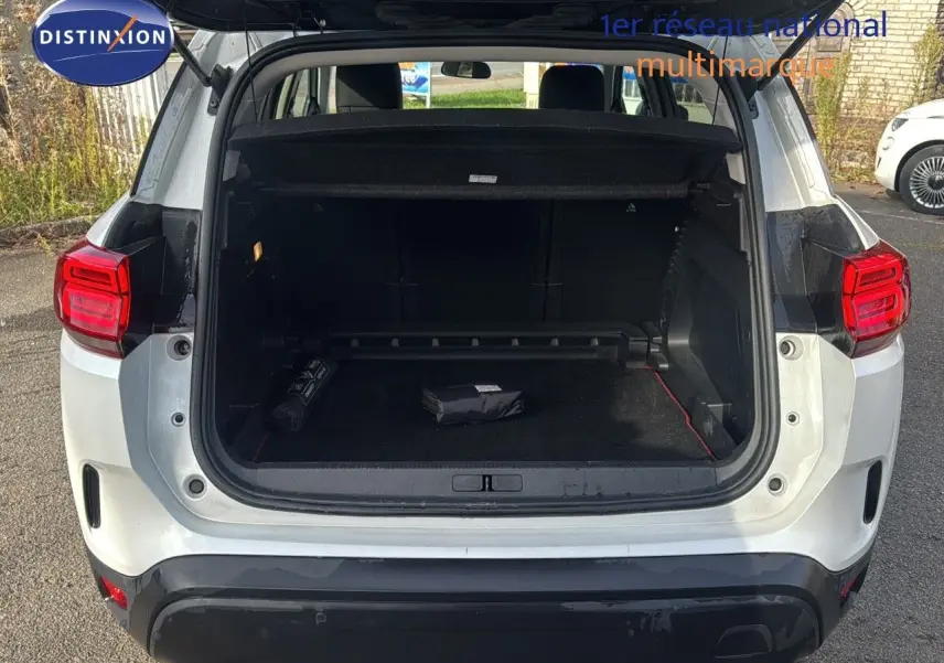 Vue arrière du Citroën C5 Aircross blanc nacré métal avec coffre ouvert montrant un intérieur spacieux et noir.