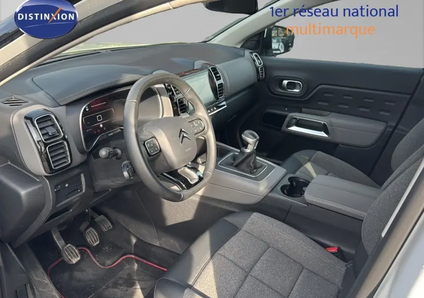 Intérieur côté conducteur du Citroën C5 Aircross blanc nacré, volant multifonction et levier de vitesse manuel visibles.