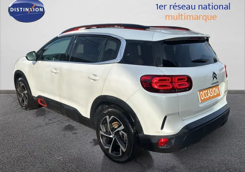 Vue 3/4 arrière droite d'un Citroën C5 Aircross blanc nacré avec jantes bi-ton et détails rouges sur les bas de caisse.