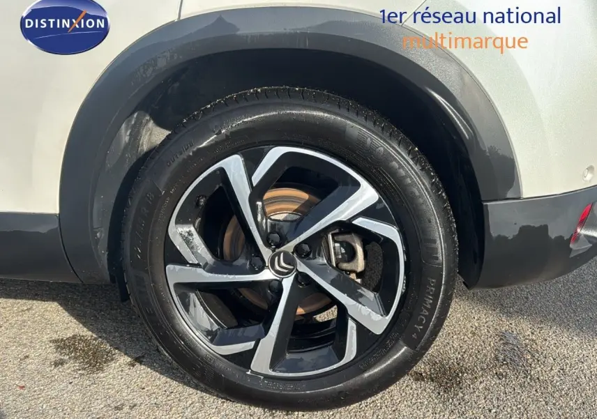 Gros plan sur la roue arrière droite d’un Citroën C5 Aircross blanc nacré avec jante alliage bicolore noire et argent.