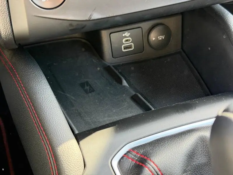 Gros plan sur la console centrale de la Ford Focus SW 2023, montrant la prise USB, prise 12V et zone de charge sans fil.