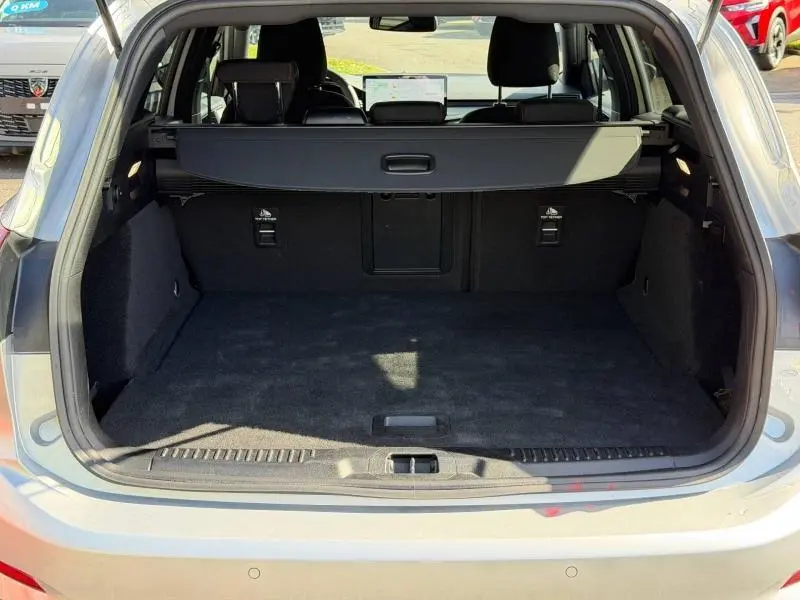 Vue arrière ouverte du coffre spacieux d'une Ford Focus SW 2023 gris lunaire métallisé avec cache-bagages déployé.