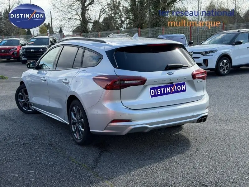 Vue 3/4 arrière droite d'une Ford Focus SW 2023 gris lunaire métallisé avec vitres teintées et double sortie d'échappement.