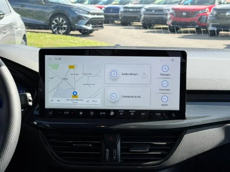 Vue intérieure centrée sur l'écran tactile du tableau de bord de la Ford Focus SW 2023, avec affichage de navigation et commandes digitales.