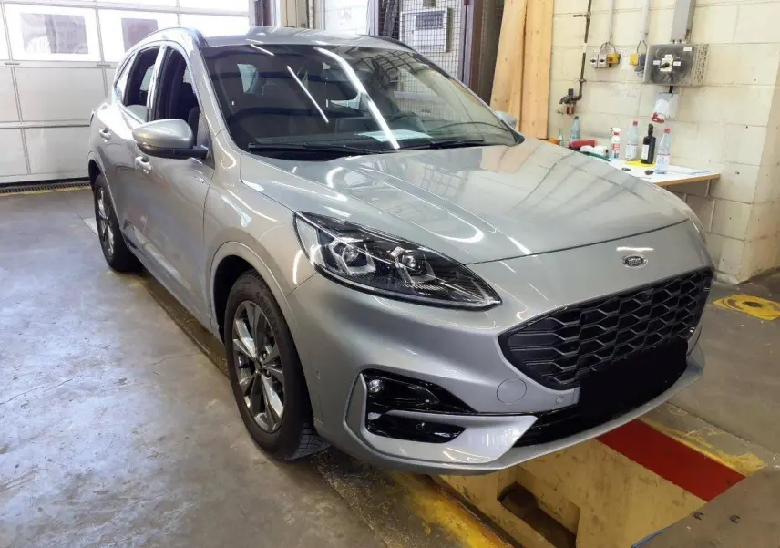 Ford Kuga 2024 gris Solar en 3/4 avant droit, avec calandre noire et jantes alliage 18 pouces ST-Line.