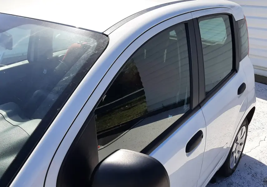 Vue de côté droit avant d'une Fiat Panda blanche 2018, mettant en valeur les vitres teintées et les poignées noires.
