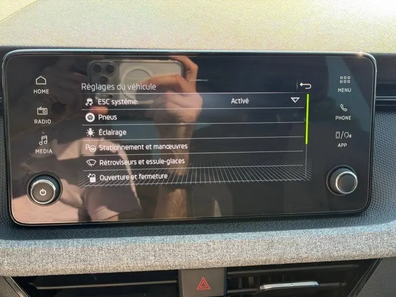 Écran tactile central du Skoda Scala 2025 affichant les réglages du véhicule, avec cadre noir et commandes tactiles.