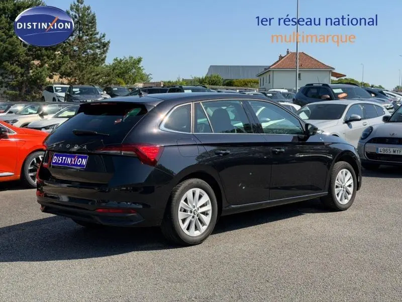 Vue 3/4 arrière droite d'une Skoda Scala noire Magic nacré avec jantes alu, stationnée en extérieur sur parking.