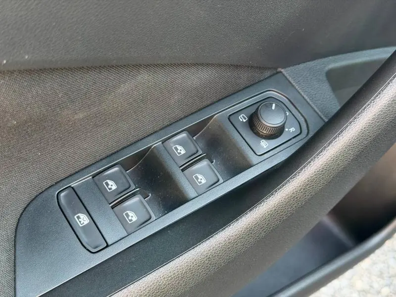 Gros plan sur les commandes de lève-vitres et rétroviseurs côté conducteur d'une Skoda Scala noir Magic nacré.