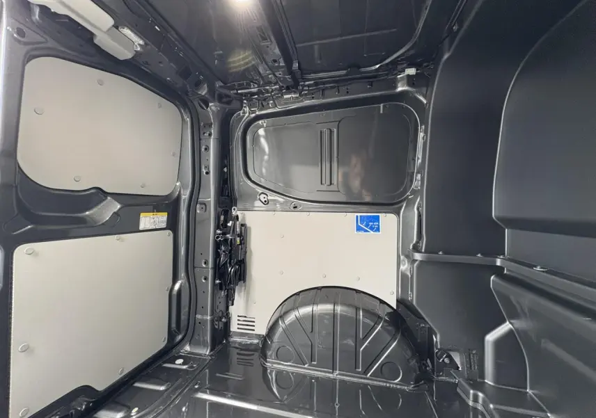 Vue intérieure de la zone de chargement du Volkswagen Transporter T7 ProCab graphite métallisé, montrant les parois et plancher métalliques.