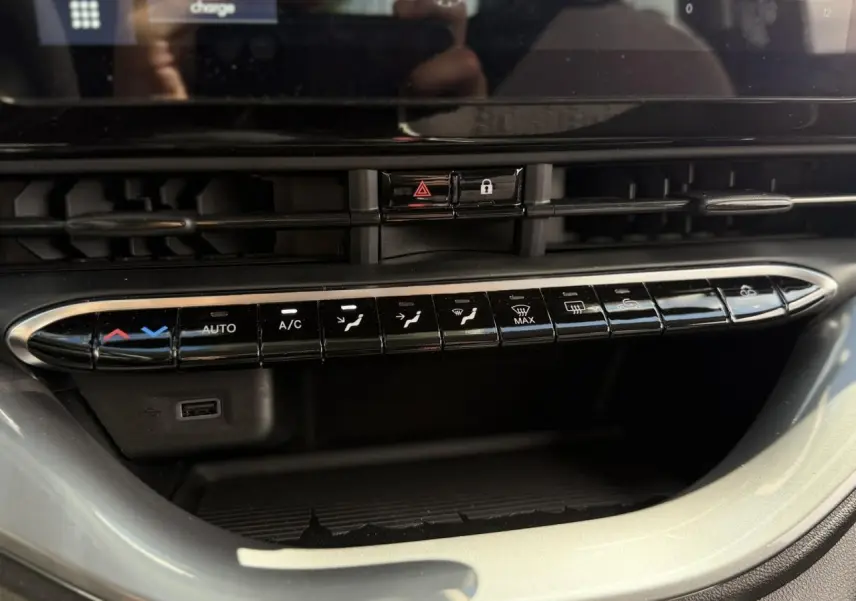 Gros plan sur la console centrale noire du Fiat 500 électrique 2024, mettant en valeur les commandes de climatisation et ventilation.