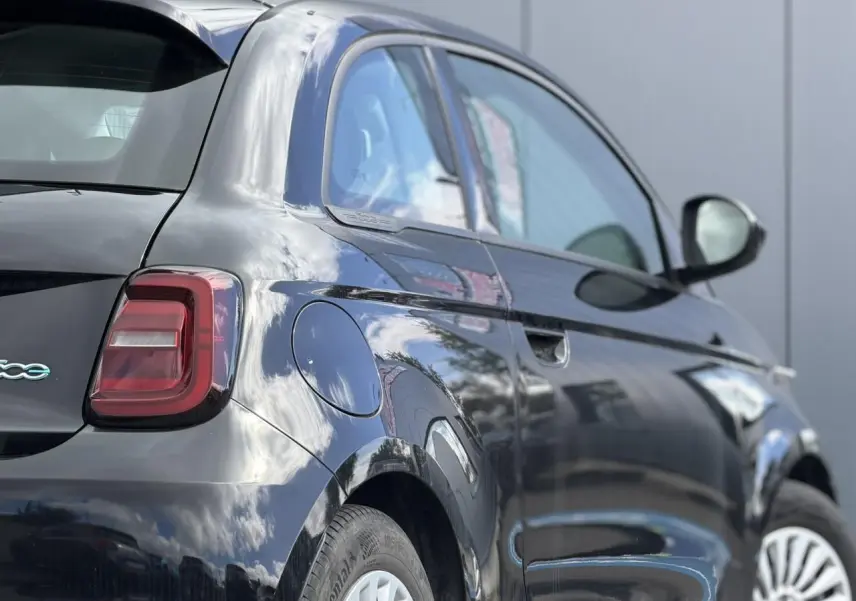 Vue 3/4 arrière droite de la Fiat 500 électrique 2024 en noir Onyx avec feux arrière LED et jantes blanches.