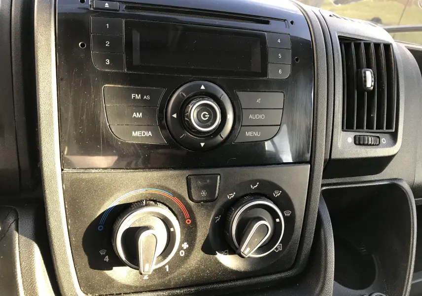 Tableau de bord intérieur du Peugeot Boxer 2014, vue rapprochée sur la console centrale avec commandes audio et climatisation.