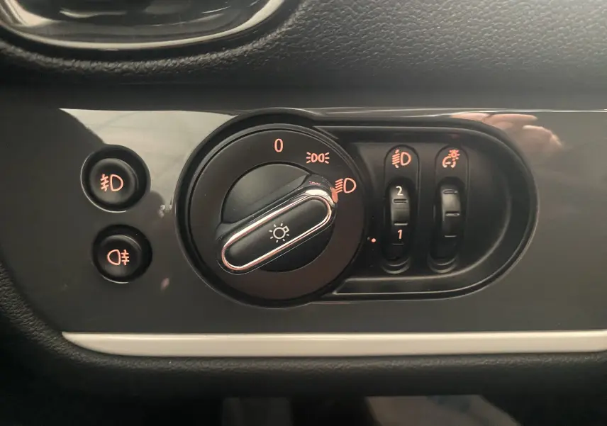 Gros plan sur les commandes d'éclairage du tableau de bord d'une MINI Countryman rouge toit noir de 2018.