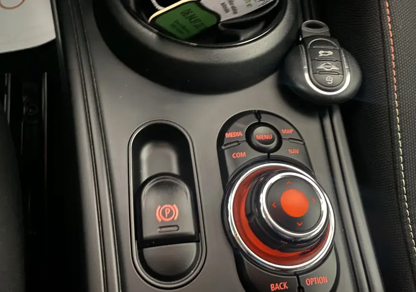 Gros plan sur la console centrale noire du MINI Countryman rouge, avec molette de contrôle et clé intelligente visible.