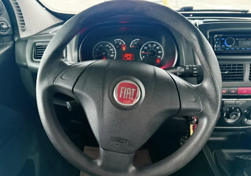 Vue rapprochée du volant noir avec logo FIAT rouge, tableau de bord et console centrale d’un Fiat Doblo Cargo 2011.