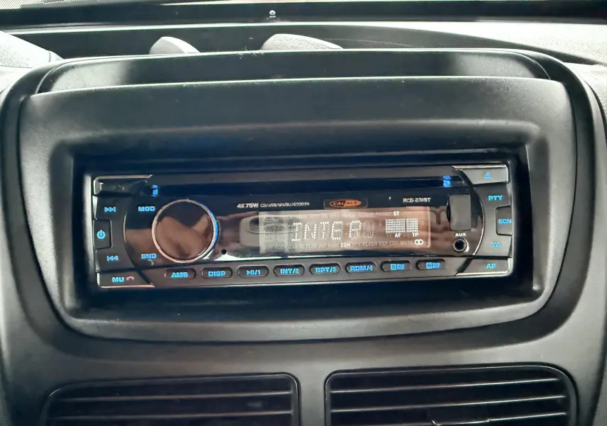 Gros plan sur la radio noire intégrée au tableau de bord du Fiat Doblo Cargo rouge de 2011.