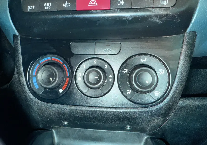 Gros plan sur les commandes de climatisation et boutons de sécurité du tableau de bord du Fiat Doblo Cargo 2011.
