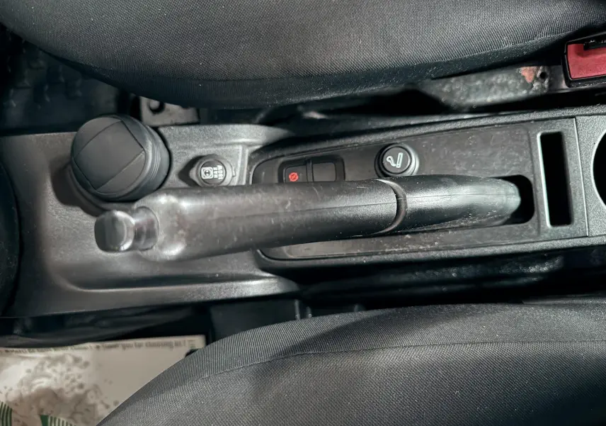 Vue rapprochée de la console centrale du Fiat Doblo Cargo 2011, montrant le frein à main et les commandes noires.