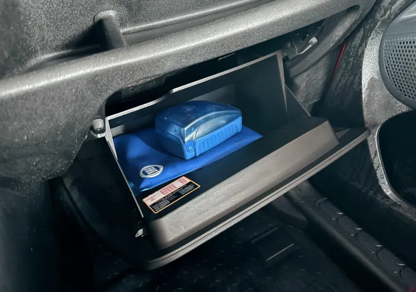 Gros plan sur la boîte à gants ouverte du Fiat Doblo Cargo 2011, avec trousse de secours bleue visible à l'intérieur.