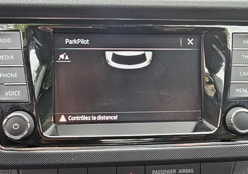 Écran central tactile du système de navigation Amundsen sur Skoda Fabia blanche, affichant l'aide au stationnement ParkPilot.