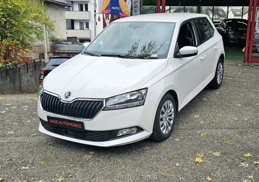 Vue 3/4 avant droite d'une Skoda Fabia blanche Cristal avec calandre noire et enjoliveurs 15 pouces visibles.