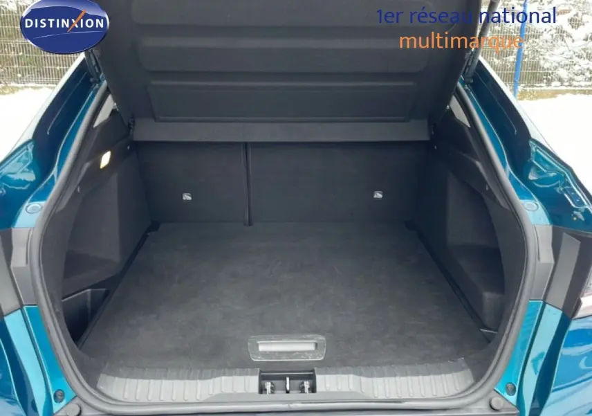 Coffre ouvert vu de l'arrière d'une Renault Arkana bleu Zanzibar métal, montrant l'espace de chargement vide.
