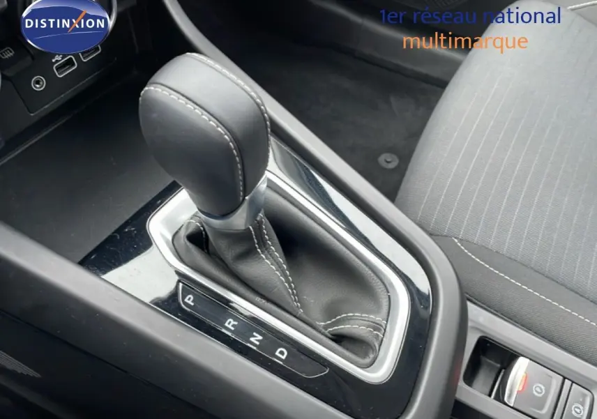 Gros plan sur la commande de boîte automatique et la sellerie tissu gris à coutures blanches dans un Renault Arkana 2025.