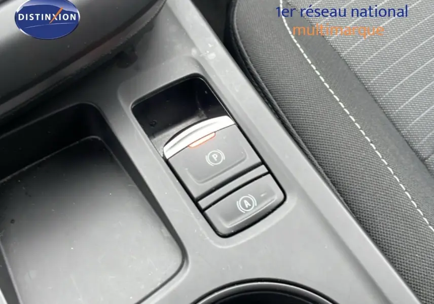 Gros plan sur la console centrale du Renault Arkana 2025, montrant les boutons de frein à main électronique et auto hold, intérieur tissu noir.