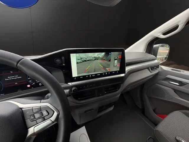 Vue intérieure côté conducteur du Volkswagen Transporter ProCab 2026, tableau de bord avec écran tactile de caméra de recul.