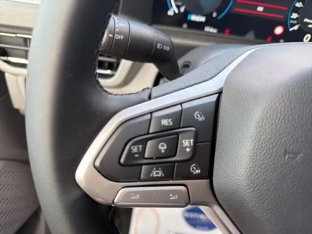 Gros plan sur les commandes au volant à droite du Volkswagen Transporter ProCab gris, affichage numérique en arrière-plan.