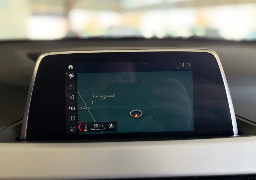 Écran GPS intégré au tableau de bord d’une BMW X1 noire, affichant une carte de navigation en intérieur.