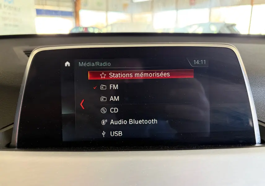 Écran central du système multimédia de la BMW X1 20i noir, affichant les options radio et Bluetooth.
