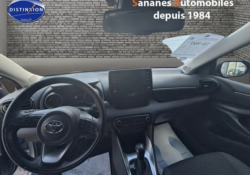 Vue intérieure avant de la Toyota Yaris Hybrid 116h 2023, tableau de bord et volant noirs avec écran tactile central.
