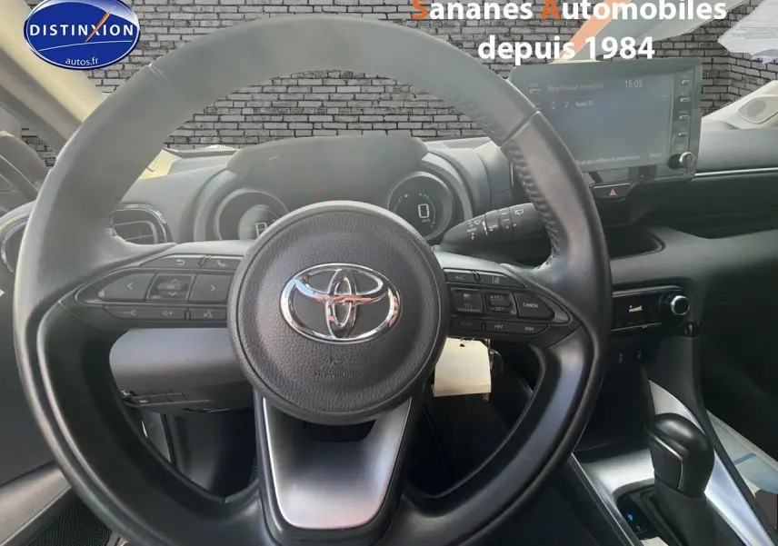 Vue intérieure centrée sur le volant noir de la Toyota Yaris Hybrid 2023 avec tableau de bord et écran tactile visible.