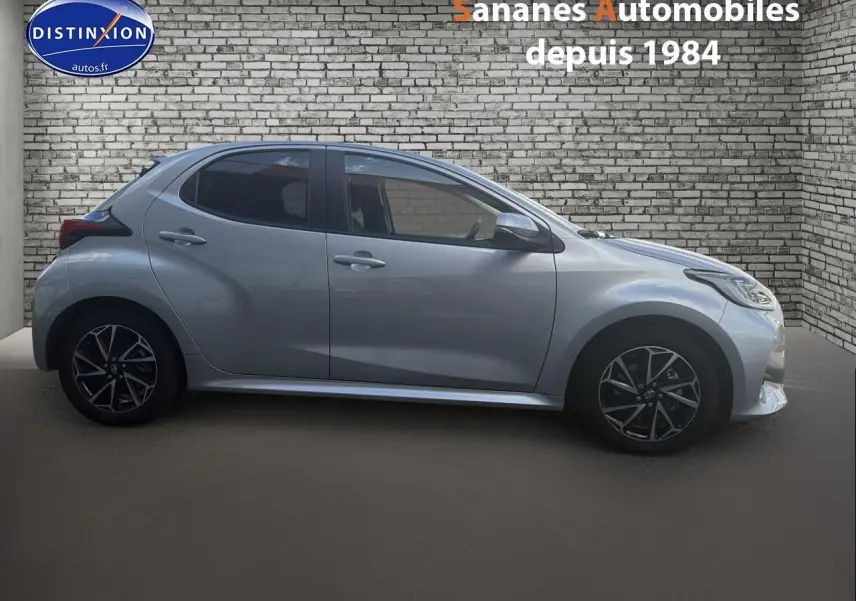 Profil droit d'une Toyota Yaris Hybrid 116h 2023 gris métallisé avec jantes alliage bi-ton et vitres arrière surteintées.