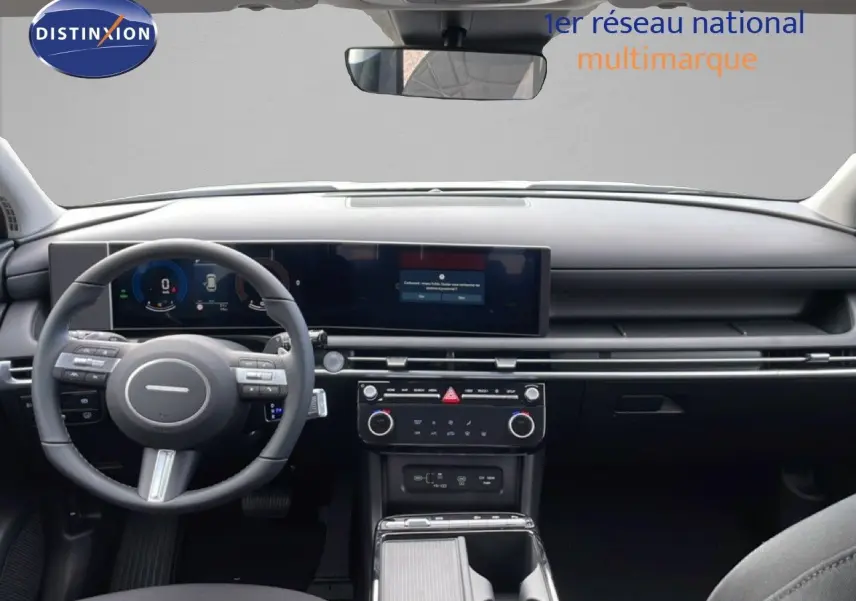 Vue frontale de l’habitacle du Hyundai Tucson blanc Atlas 2026, tableau de bord numérique et volant multifonction.
