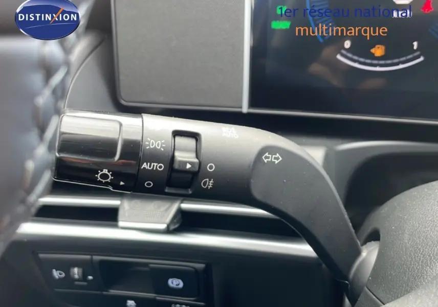 Gros plan sur la manette de clignotants à gauche du volant du Hyundai Tucson blanc, avec tableau de bord numérique en arrière-plan.