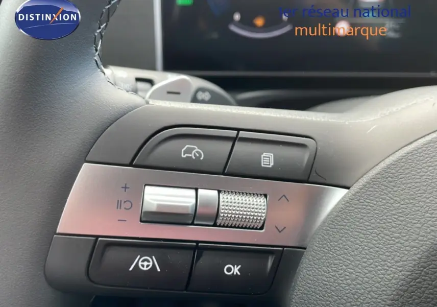 Gros plan sur les commandes multifonctions au volant du Hyundai Tucson 2026, finition blanche avec détails en métal brossé.
