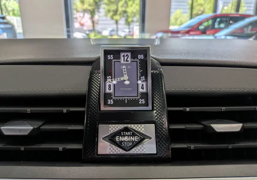 Gros plan sur l'horloge analogique et le bouton start/stop du tableau de bord du DS7 gris 2024.