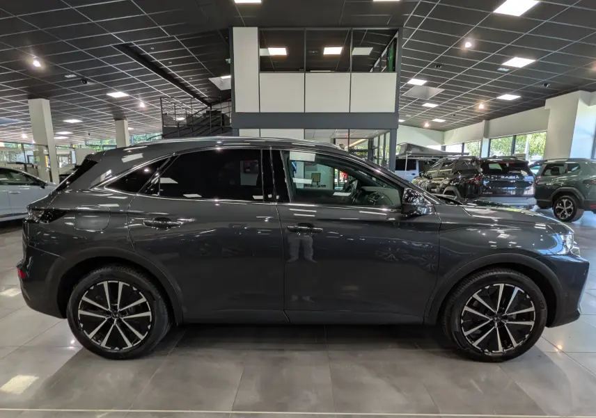 Vue latérale droite du SUV DS7 BlueHDi gris foncé 2024 avec jantes alliage bicolores en concession.